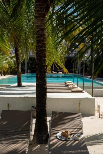 a table and chairs next to a pool with palm trees at Casa Beach Hotel "Casa Del Mar" in Jambiani