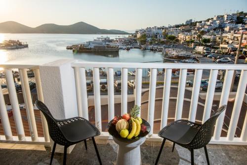 a balcony with two chairs and a bowl of fruit at Kalypso Suites Hotel - Adults Only in Elounda