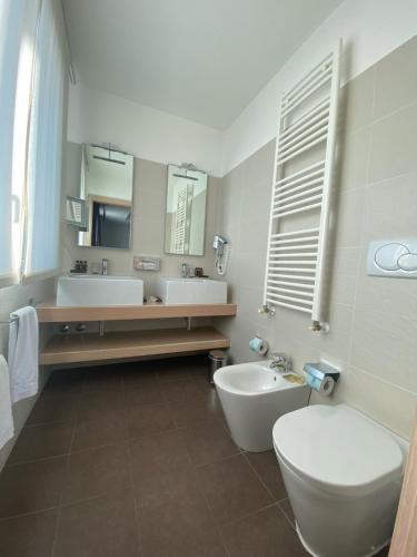 a bathroom with two sinks and a toilet and a mirror at Card International Hotel in Rimini