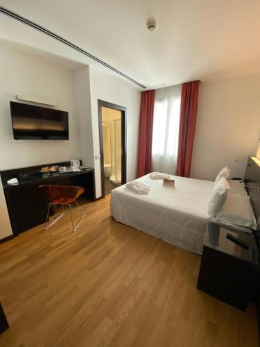 a bedroom with a bed and a desk and a television at Card International Hotel in Rimini