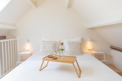 a bedroom with a white bed with a wooden table at Op Oost Boutique hotel & Restaurant het Kook Atelier in Oosterend