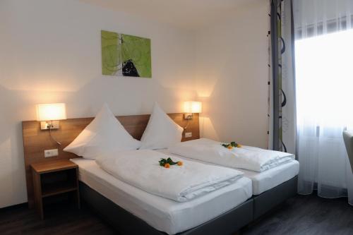 two beds in a hotel room with flowers on them at Hotel Lamm in Waiblingen