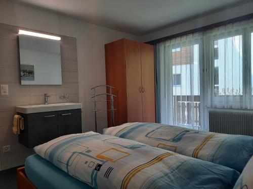 a bedroom with two beds and a sink and a window at Apartments Alpenfirn Saas-Fee in Saas-Fee