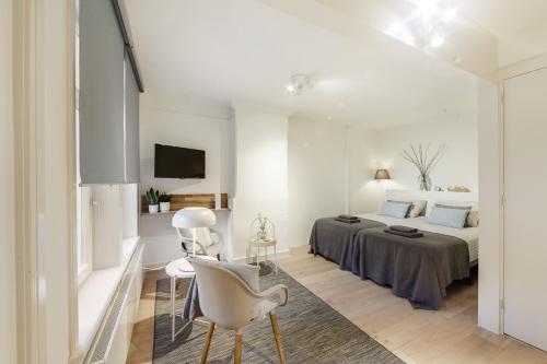 een witte slaapkamer met een bed en een tafel en stoelen bij Adam's Suite in Amsterdam