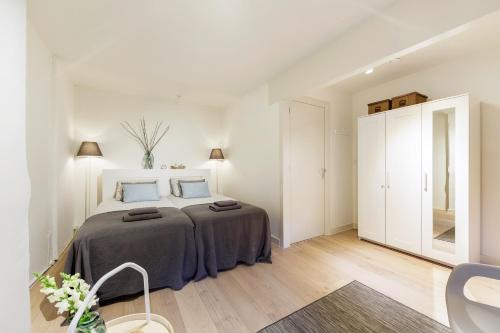 a white bedroom with a large bed with blue pillows at Adam's Suite in Amsterdam