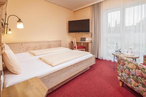 a bedroom with a bed and a desk and a window at Hotel Am Kamin in Kaufbeuren