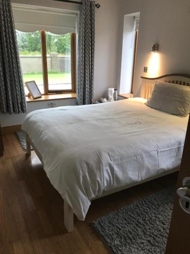 a bedroom with a large white bed with a window at Laithreach Briuin B&B W23E0H9 in Maynooth