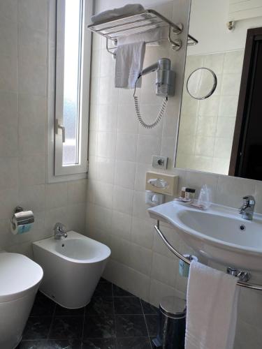 a white bathroom with a sink and a mirror at Card International Hotel in Rimini