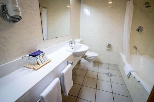 a bathroom with a sink and a tub and a toilet at Comfort Hotel Flames Whangarei in Whangarei