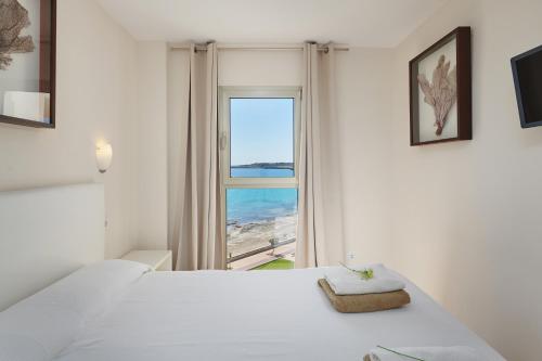 a white bedroom with a view of the beach at SA MANIGA 6-H in Cala Millor
