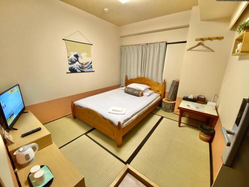 徳島市にあるGuestHouse017徳島個室 飲食街中心 阿波踊り会館7分 文理&徳島大学 アスティとくしま車8分のベッド、机、テレビのある寝室