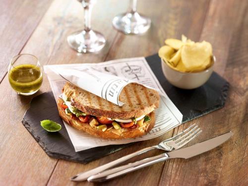 a sandwich on a black plate with a bowl of cheese at Ibis Brussels Erasmus in Brussels