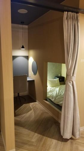 1 dormitorio con cama y cortina en Good Bless Garden Sauna&Stay en Yonago