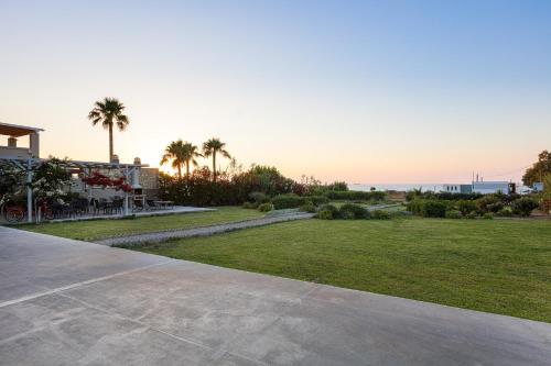 a view of a yard with palm trees and the ocean at Adele Riva in Adelianos Kampos