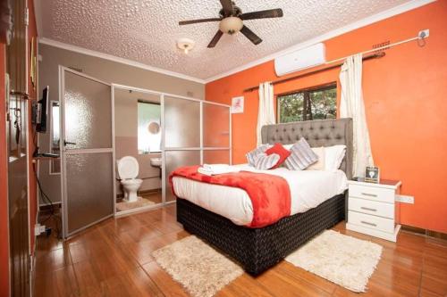 a bedroom with a bed with an orange wall at Sweet Holiday Homes in Victoria Falls
