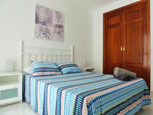 1 dormitorio con 1 cama con edredón a rayas en alquilaencanarias El Medano, El Cabezo, next to the beach !!!, en El Médano