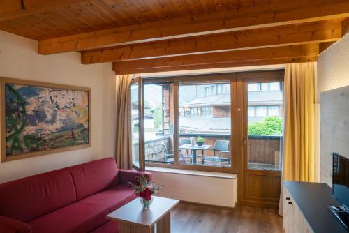 a living room with a red couch and a large window at Aparthotel Schindlhaus und Koia Premium Apartments in Söll
