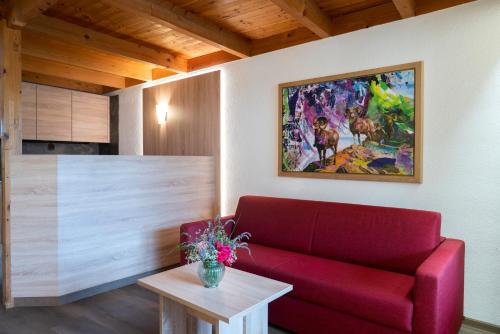 a living room with a red couch and a table at Aparthotel Schindlhaus und Koia Premium Apartments in Söll