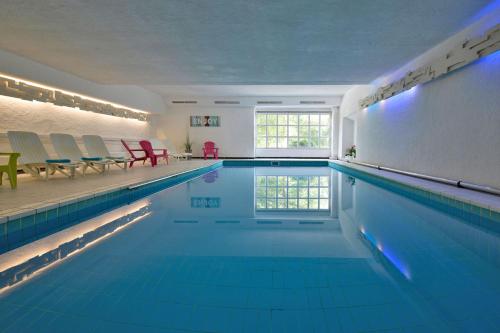a large swimming pool with blue water in a room at Gut Funkenhof in Sundern