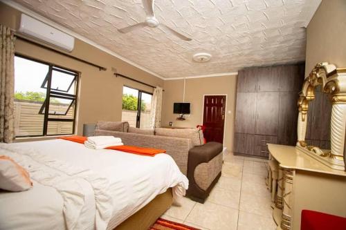 a bedroom with a bed and a couch and a table at Sweet Holiday Homes in Victoria Falls