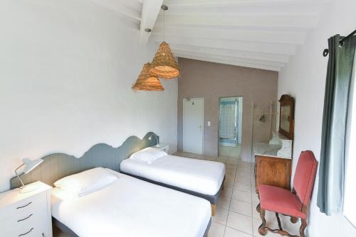 a room with two beds and a red chair at Auberge La Plaine in Chabrillan