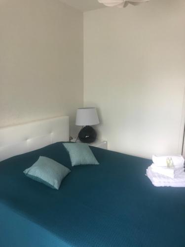 uma cama azul com duas almofadas num quarto em Chambres Les Passiflores em Saint-Palais-sur-Mer
