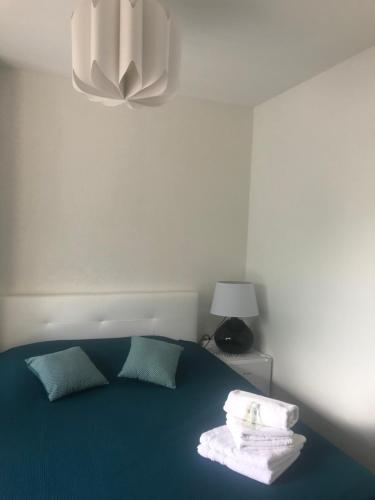 um quarto com uma cama azul com toalhas em Chambres Les Passiflores em Saint-Palais-sur-Mer