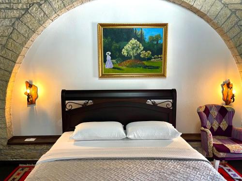 a bedroom with a bed and a painting on the wall at White House Berat in Berat
