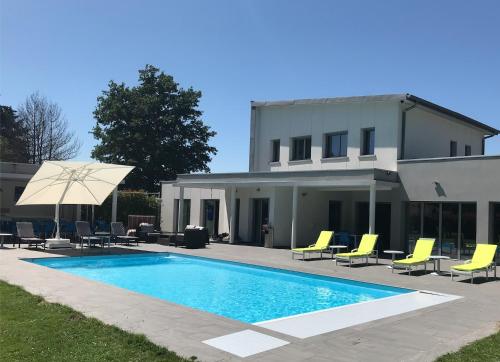 uma piscina com cadeiras e um guarda-sol ao lado de uma casa em Domaine Georges V em Saint-Junien