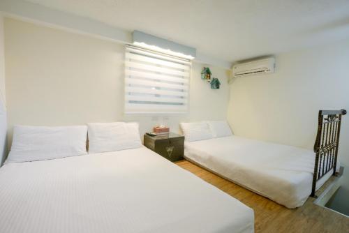 a bedroom with two white beds and a window at 高雄市包棟民宿-高雄寵物友善民宿-高雄阿爾兔兔民宿-Rabbit house in Kaohsiung