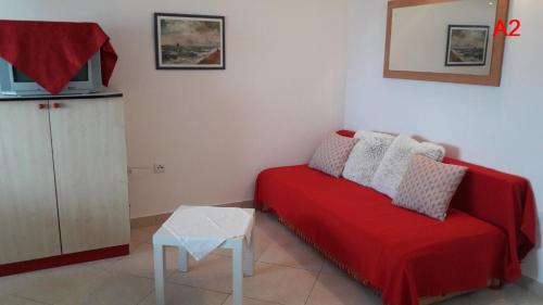 een woonkamer met een rode bank en een tafel bij Kamena kuca Smiljevac - Stone house Apartment 2 in Ližnjan