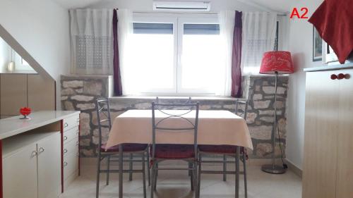 een keuken met een tafel met stoelen en een raam bij Kamena kuca Smiljevac - Stone house Apartment 2 in Ližnjan