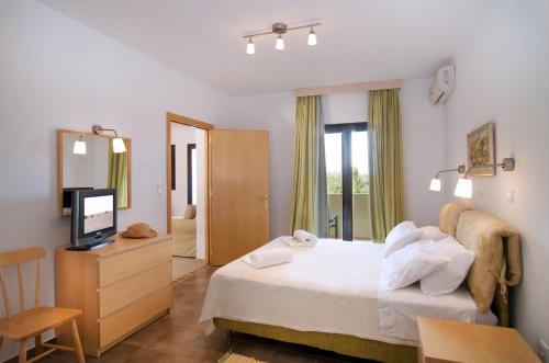 a hotel room with a bed and a television at Miraluna Aparthotel in Lefkos Karpathou