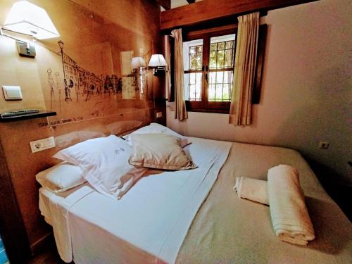 Apartamentos Alhambra في غرناطة: غرفة نوم بسرير ذو شراشف ووسائد بيضاء