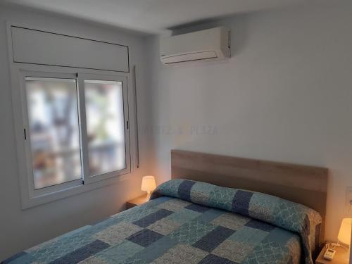 a bedroom with a bed and two windows at Apartamentos Dins Mar Apto. 1 in Torredembarra