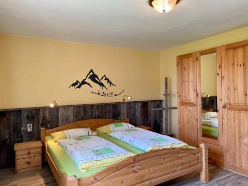 Un dormitorio con una cama de madera con montañas en la pared en Im-Oberland - Tal - KönigsCard, en Bad Kohlgrub