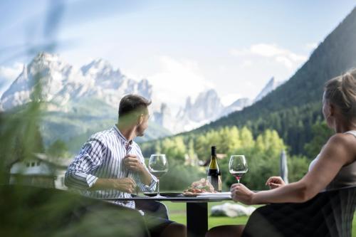 a man and a woman sitting at a table with wine glasses at Aparthotel Gamz in Sesto