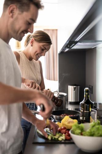 a man and a woman preparing food in a kitchen at Aparthotel Gamz in Sesto