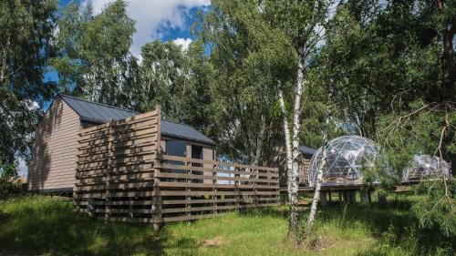 a wooden fence next to a cabin in a field at JURA GLAMP luksusowe całoroczne domki na wyłączność KOPUŁY IGLOO taras ogród in Wola Kalinowska