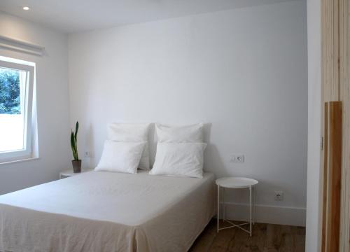 Dormitorio blanco con cama con sábanas y almohadas blancas en ESTUDIO BEDANDBEACH, en El Palmar