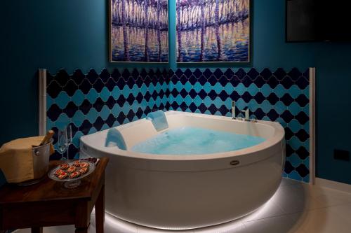 a large tub in a bathroom with blue walls at Hotel Sicilya in San Vito lo Capo