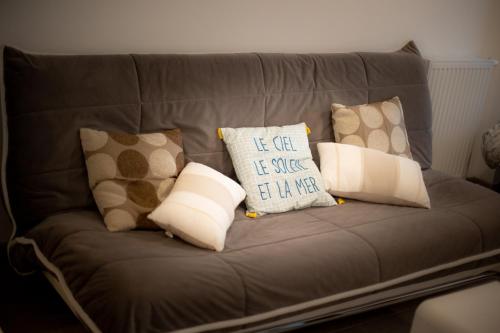 a gray couch with pillows on it at Appartement T1bis centre ville Andernos Les Bains in Andernos-les-Bains