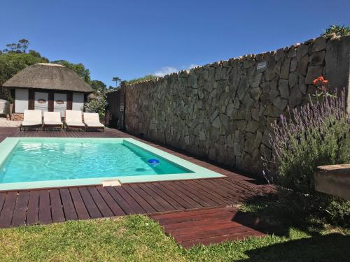 un patio trasero con piscina y pared de piedra en Esteños de la Pedrera Posada y Spa en La Pedrera