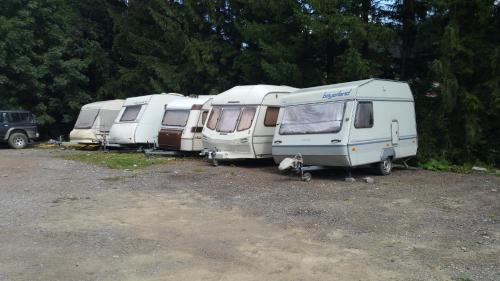 a group of three trailers parked in a parking lot at Camping Aviator Busteni, Parcare rulota termen lung (6-12 luni). in Buşteni