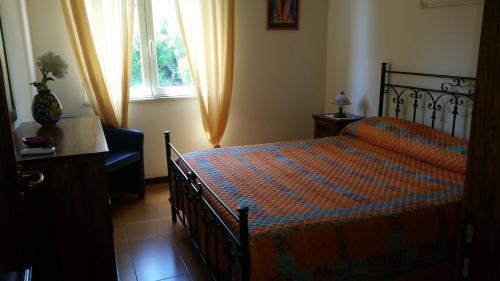 a bedroom with a bed and a chair and a window at Villa Carmelas in Taormina