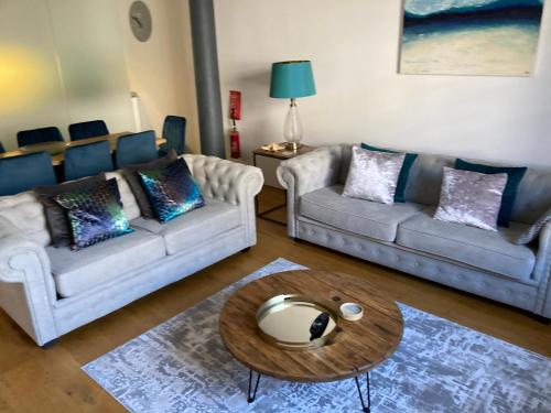 a living room with two couches and a coffee table at Luxurious "THE BRUCE" - - LARGE FAMILY APARTMENT and DELUXE STUDIO That CONNECT IN PRIVATE LOBBY - - Beautifully Refurbished - - FREE Onsite PARKING in Plymouth