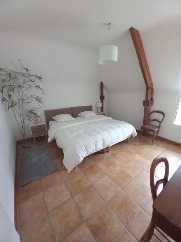 a bedroom with a white bed and a table and chair at l'orangerie in Pontivy