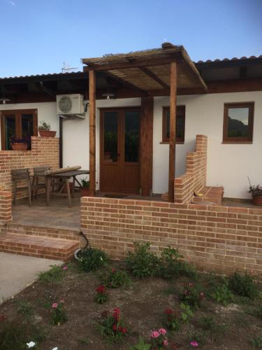 une maison avec un mur en briques et une pergola en bois dans l'établissement Agriturismo Le Terre Di Zoe', à Limbadi