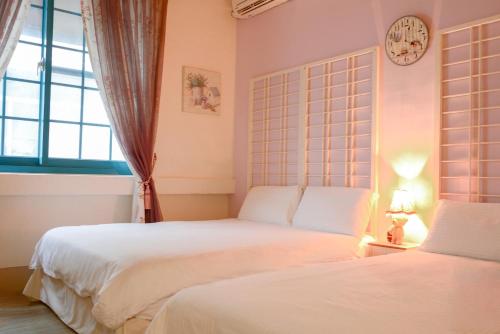 a bedroom with two beds and a clock on the wall at 高雄市包棟民宿-高雄寵物友善民宿-高雄阿爾兔兔民宿-Rabbit house in Kaohsiung