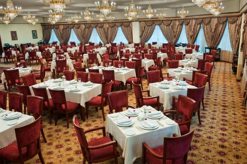 a banquet hall with white tables and chairs and chandeliers at Ramada Plaza by Wyndham Gence in Ganja